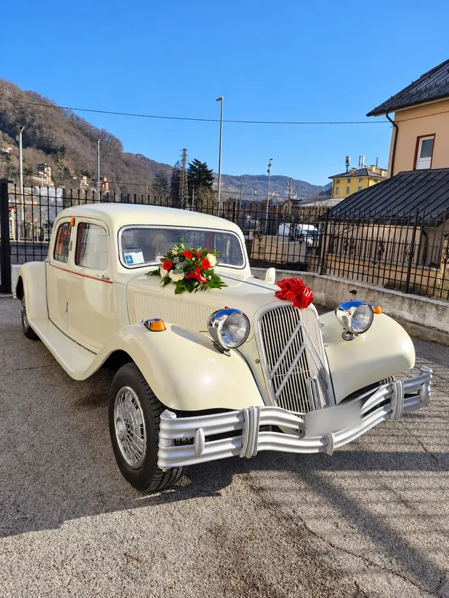 Auto d’epoca bianco crema con fiori rossi e bianchi e un fiocco rosso