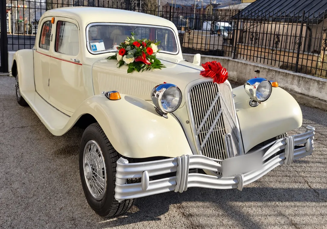 Auto d’epoca bianco crema con fiori rossi e bianchi sul cofano